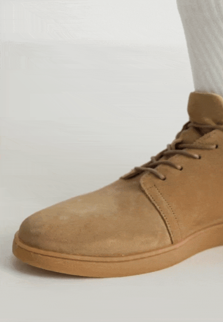 A short video of a person’s hands zipping and unzipping a pair of Adaptive light brown suede boots, worn by someone with a prosthetic leg.