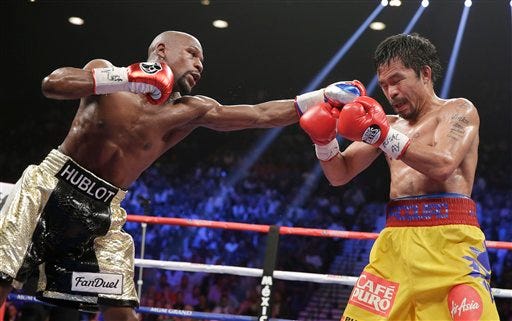 Floyd Mayweather Jr., left, stops Manny Pacquiao, from the Philippines, with a left during their welterweight title fight on Saturday, May 2, 2015 in Las Vegas. (AP Photo/Isaac Brekken)