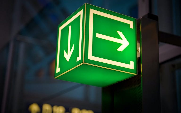 A green sign in the shape of a box with arrows on each side lighting up