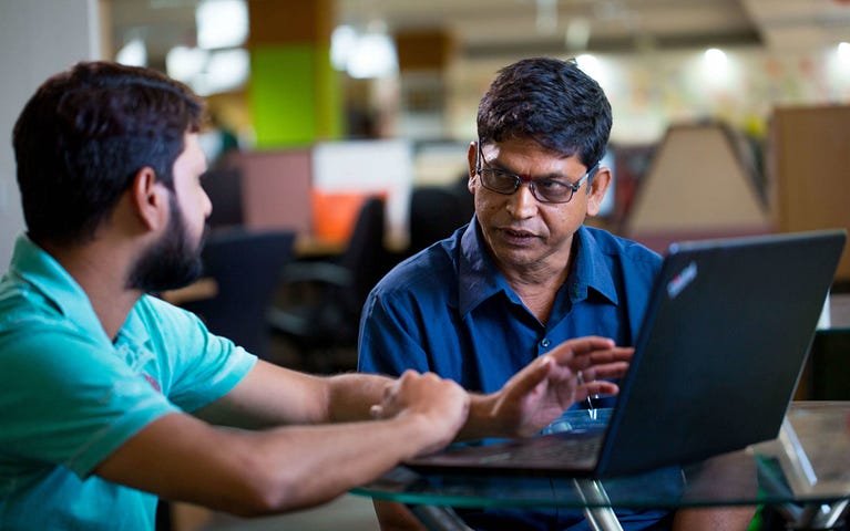 Two men in a discussion, sitting in front of a laptop