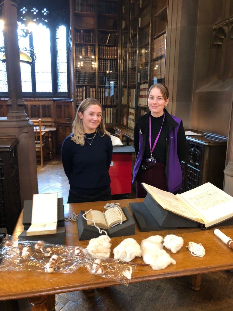 Two young women behind a desk showing books and historical artefacts