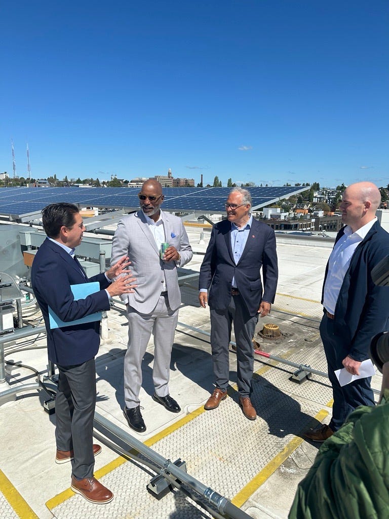 Group of four people standing on a rooftop in front of solar panels