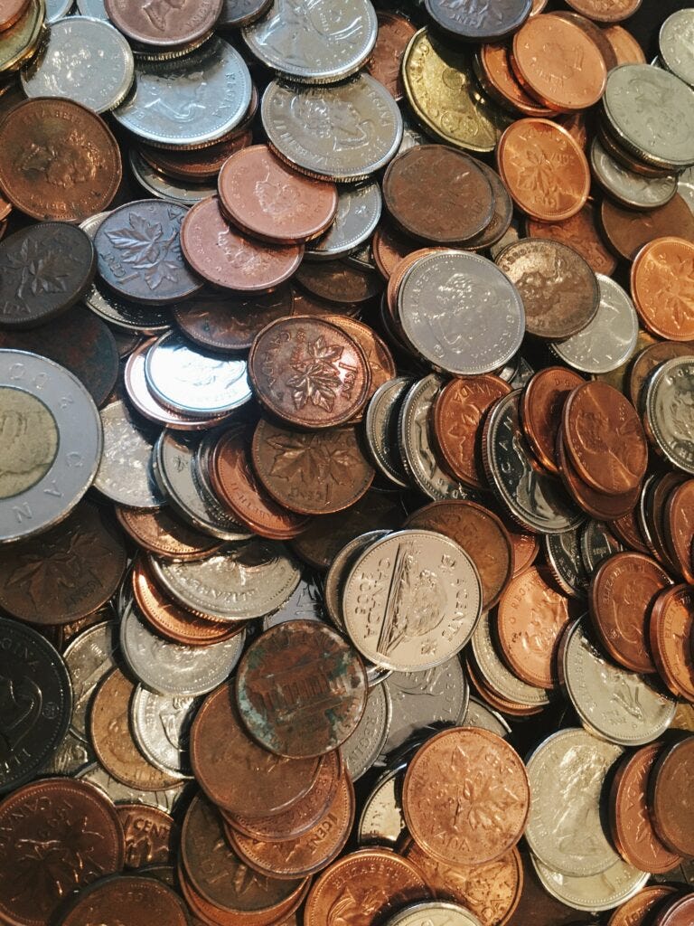 A pile of loose Canadian change and a 5 cent coin with a beaver in the middle. Image courtesy of Pina Messina at Unsplash.