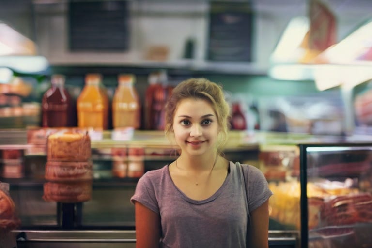 A happy looking young woman behind the deli counter at a supermarket, before she talks to Howard Bubski.