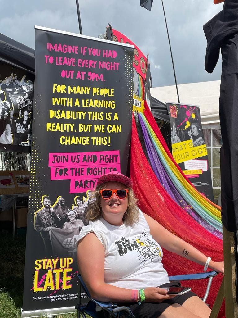 Someone sat in front of a banner saying ‘Imagine if every night out ended at 9pm. For many people with a learning disability this is a reality. But we can change this! Join us and fight for the right to party!