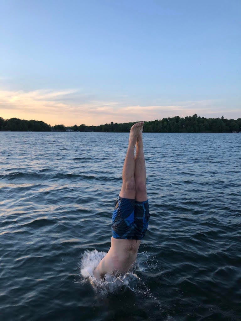 A man diving into a lake at sunset