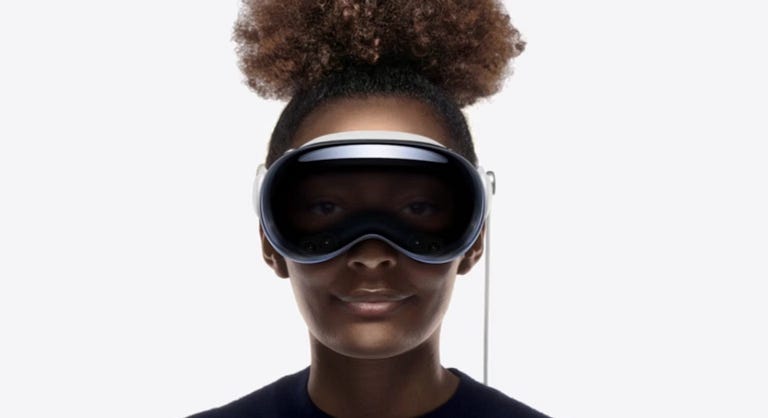 Image: A woman with an Afro wearing the Apple Vision Pro, immersed in a digital interface with vibrant visuals and augmented reality elements