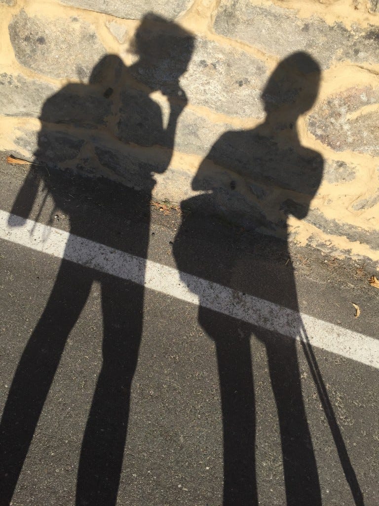 Two full body shadows on the ground, from two pilgrims