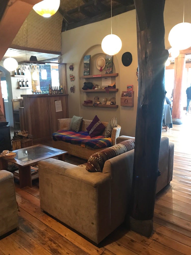 A cozy, rustic looking room with two couches, blankets, pillows and instruments on the wall and a bar in the background.