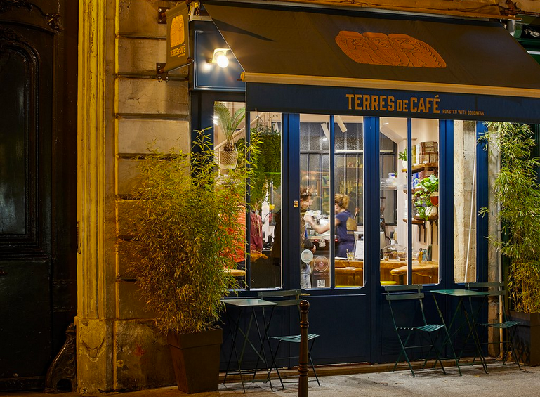 fachada de um cafe com portas e toldo azul em paris
