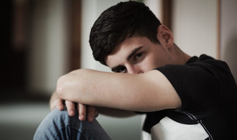 Close-up portrait of male student with head on knees