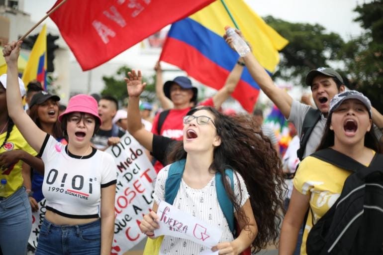 Group of young protesters with Colombian flags, protesters are screaming and marching
