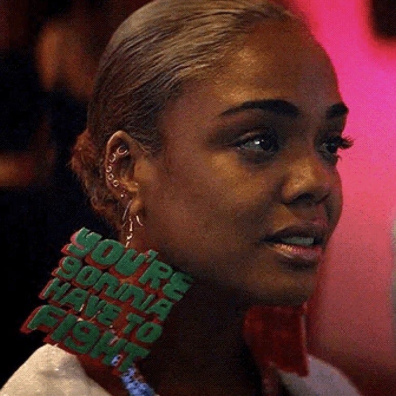 Sideview of Detroit wearing earrings, only one is visible and it says “You’re gonna have to fight”