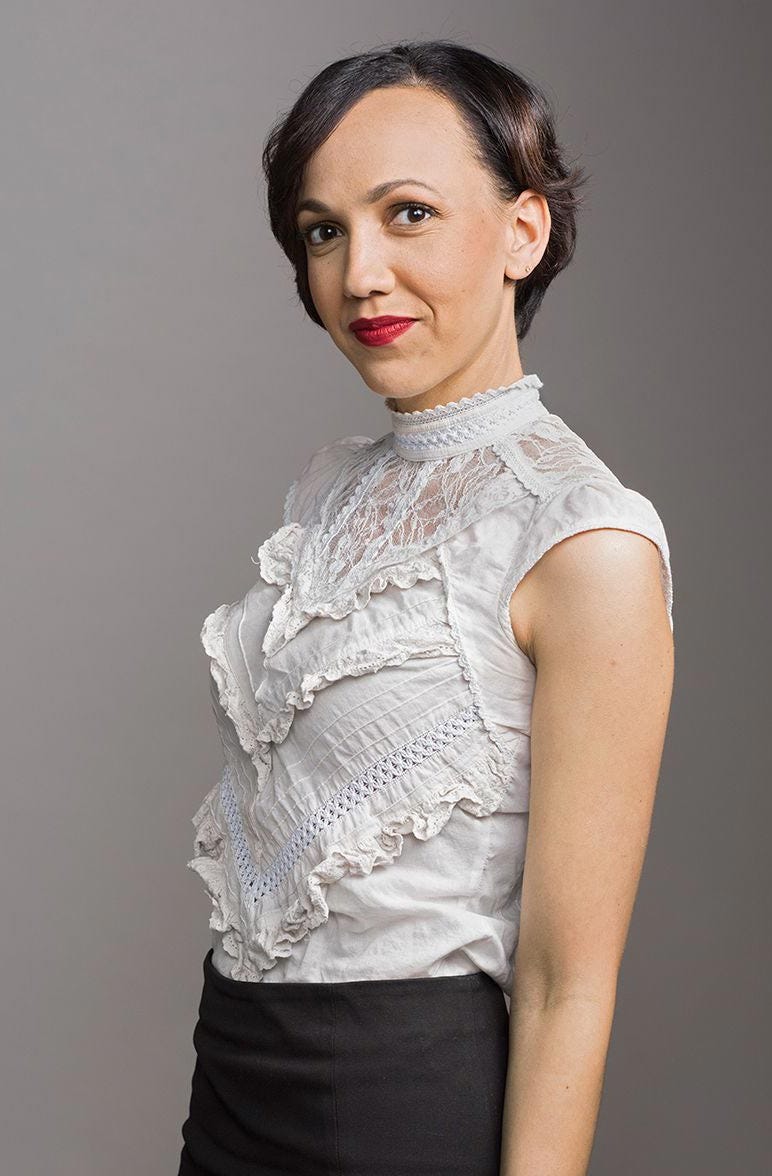 Photograph of Ashleigh Axios wearing a white blouse.