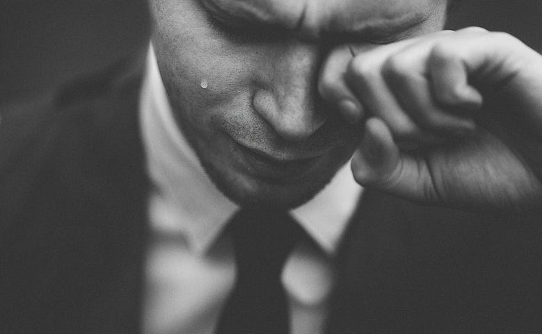 A grieving man by https://unsplash.com/photos/man-wiping-his-tears-T5lmpSYxnSU