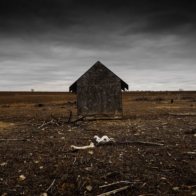A desolate shack in the middle of a dry field on a cloudy day.