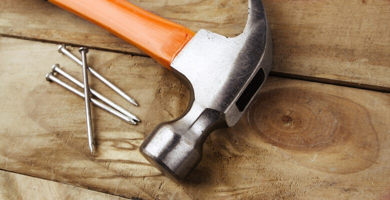 Hammer with 4 nails on a board