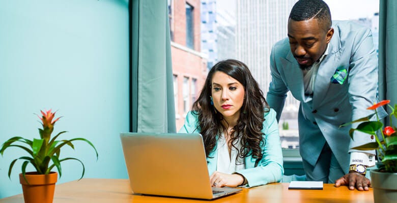 Two designers dressed in blue working on a computer.