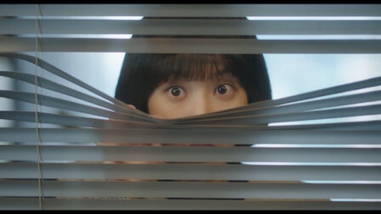 A woman, Attorney Woo Young-woo, peeks through a set of window blinds. We see only the top of her nose, her eyes, and her bangs.