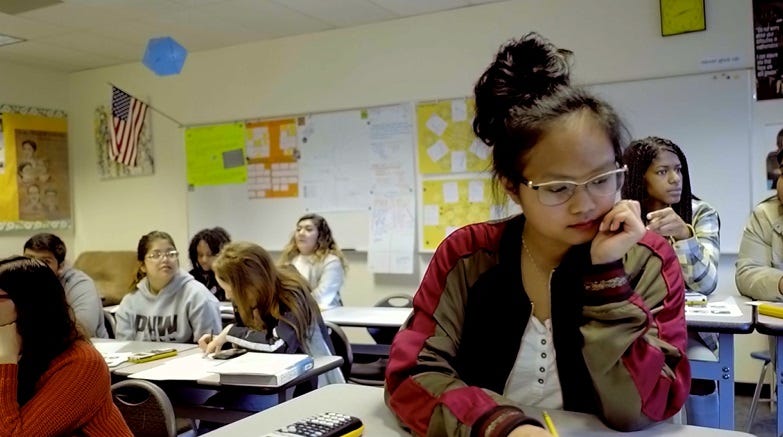 Students discuss a math problem in a classroom.