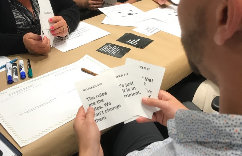 Photo of a man holding three blocker cards while playing the CaHMW game.