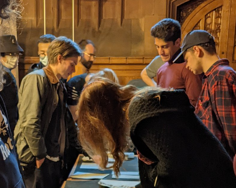 Group of students leaning over special collection table looking at objects