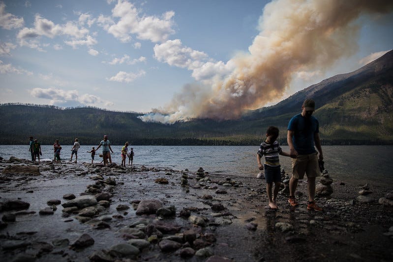 The Howe Ridge Fire from Lake McDonald Lodge with people walking around the lake edge