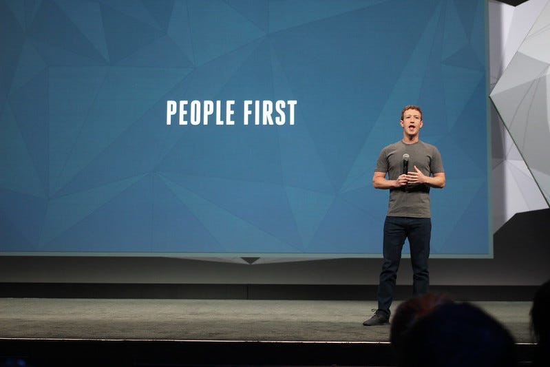 Mark Zuckerberg giving a presentation with the text “People first” written behind him