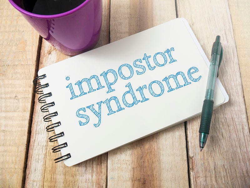 Notepad with the words “impostor syndrome” written on it.