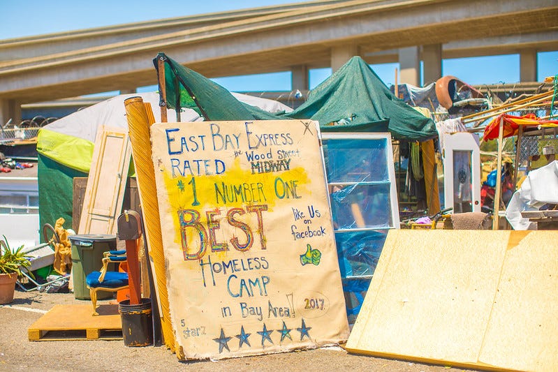 Sign reads “East Bay Express Rated #1 Number One Best Homeless Camp in Bay Area 2017. Large sign in front of a homeless camp in California.