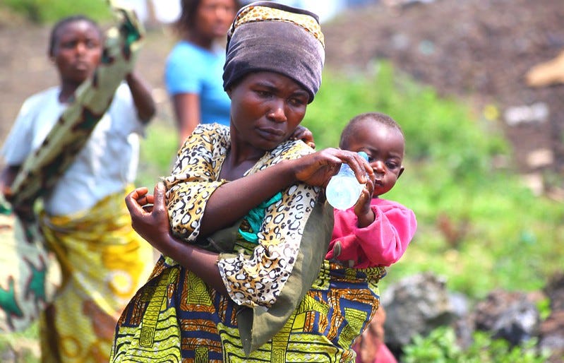 A woman gives water to her daughter in a camp in the Democratic Republic of Congo in 2013. Tens of thousands of Congolese had fled fighting in the eastern part of the African nation, seeking refuge in camps near the city of Goma. Eddy Mbuyi/Oxfam via Flickr.