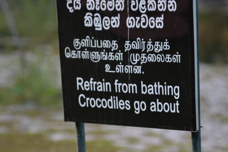 Sign saying “Refrain from bathing Crocodiles go about”