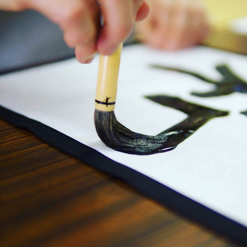 A brush full of black ink runs across a white piece of paper to form the Chinese character of Harmony at Zenpoji Temple in Tsuruoka City, Yamagata Prefecture.