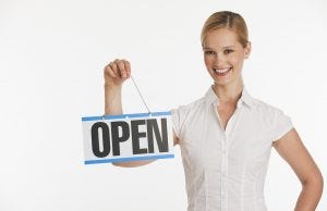 Female small business owner holding up Open sign with white seamless background