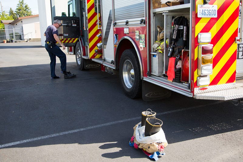 Firefighter Bob Coston slips off his shoes before changing into his bunker gear and boots at the Bellingham Fire Department training grounds on the corner or Alabama and Iron Street, Tuesday, April 26. Many firefighters will strip down to their underwear before changing into their flame-resistant bunker gear to avoid overheating and sweating through their uniform. “He’s been here since the [fire] department started [in 1904],” McDonald jokes about Coston who has been with the Bellingham Fire Department for 22 years.