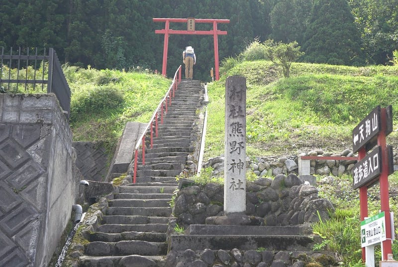 Tim Bunting AKA Kiwi Yamabushi bows at the Torii (shrine gates) to Kumano Jinja at the base of Tengu-yama. This is the main trailhead to the mountain.