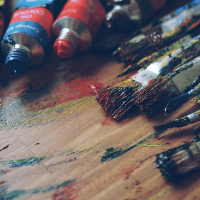 paintbrushes and paint on brown desk