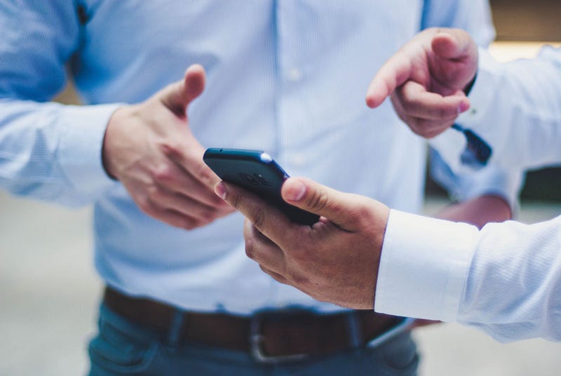 two people pointing at a smartphone with a time tracker