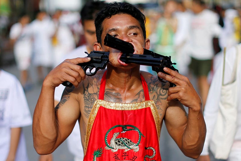 A devotee of the Chinese Samkong Shrine walks with two revolvers pierced in his mouth during a procession celebrating the annual vegetarian festival in Phuket, Thailand Octuber 4, 2016. REUTERS/Jorge Silva TPX IMAGES OF THE DAY