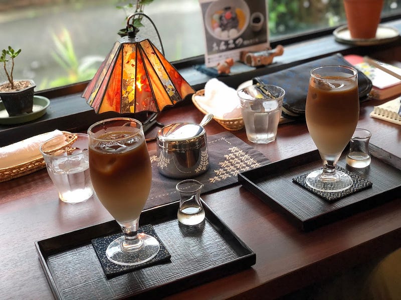 Two cold-brew lattes served with ornamental red and orange lamp in the background at Somokusha, a Japanese cafe in Matsuyama, Sakata City, near Mt. Kyogakura