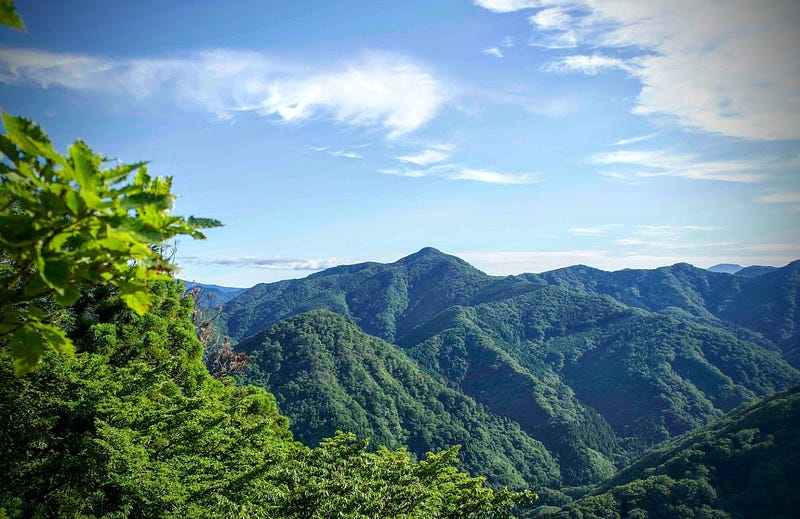 A green mountain in the distance underneath a bright blue sky seen from Mt. Kyogakura on the outskirts of Sakata City, Yamagata Prefecture, Tohoku region in north Japan.