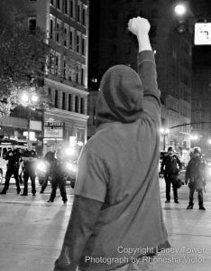 Protester raises a fist in front of Oakland police during a protest following the Grand Jury's Ferguson verdict, on the 24th.