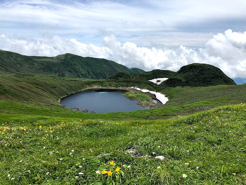 Mt. Chokai Crater Lake in the middle of summer surrounded by Dawn Lilies and snow