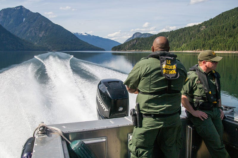 Border patrol agents Deshonn Noble, left, and Brooks Madden, right, eye the banks of Ross Lake by boat on May 14, 2016 as they return from the Hozomeen Campground straddling the Canadian border. With Ross Lake serving as an aquatic thoroughfare from the international border to Highway 20, smugglers peddle drugs through this corridor using everything from their own feet to kayaks to helicopters.