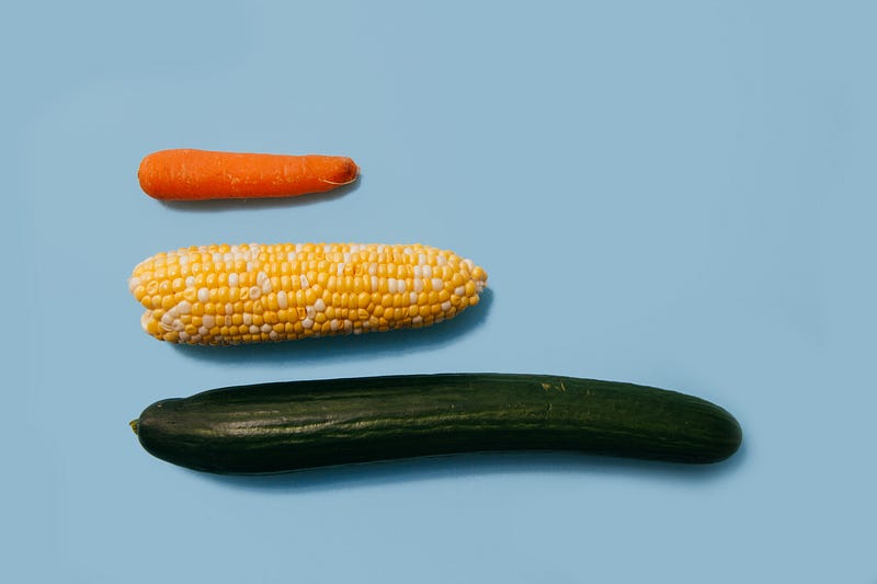 Three penis shaped vegetables line up in a row.
