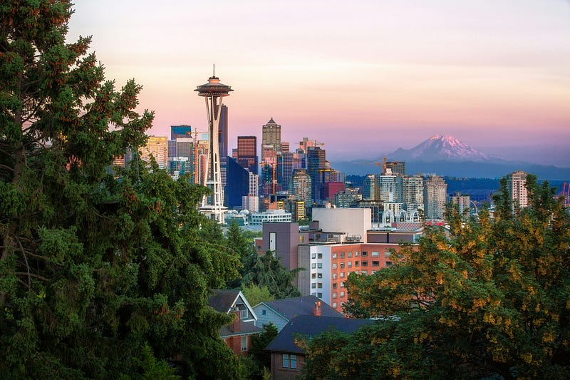 Seattle! We see the Space Needle in the foreground and Mount Ranier in the distance as the sun sets.