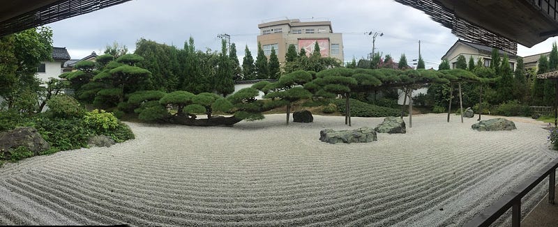 A long tree that grows sideways inside a Zen garden with freshly manicured stone landscape in Nezugaseki, a small fishing village on the Sea of Japan near Mt. Nihonkoku, one of the 100 Famous Mountains of Yamagata in Tohoku, north Japan