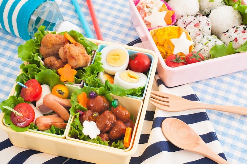 People bring drinks and bento box lunches to a hanami party