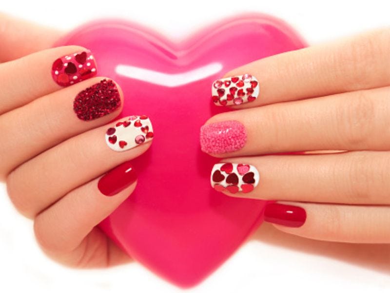 A girl holding her heart and showing different nail arts