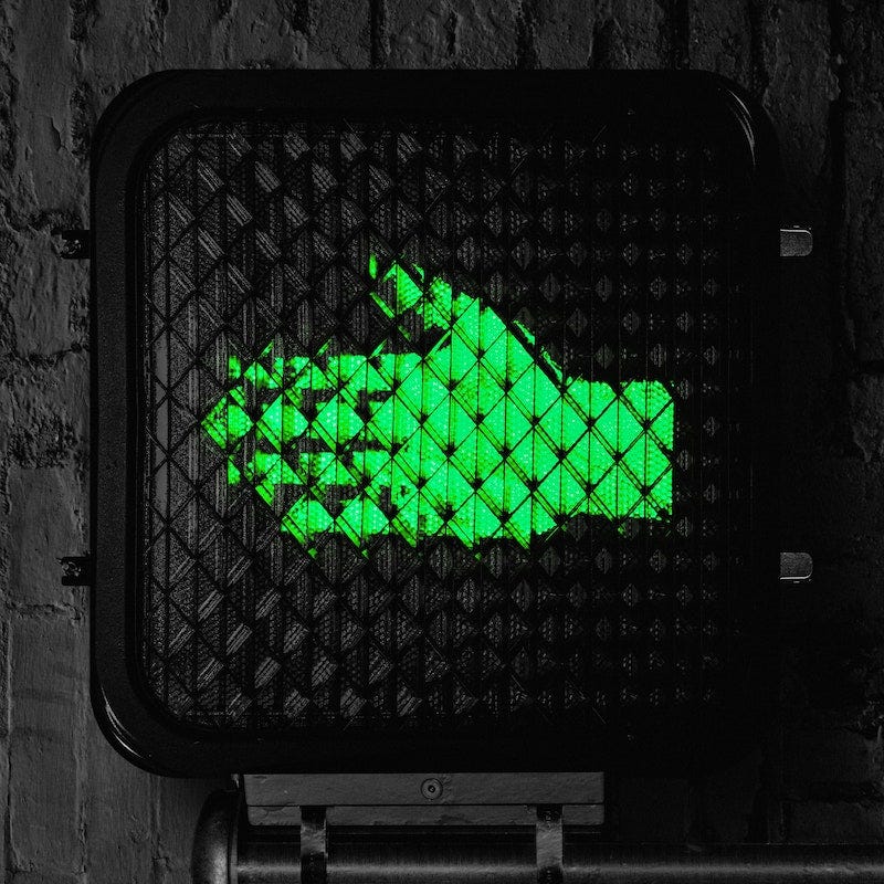 The Raconteurs “Help Us Stranger” album cover art; crosswalk signal with green hand turned horizontal to the left on painted black wall background